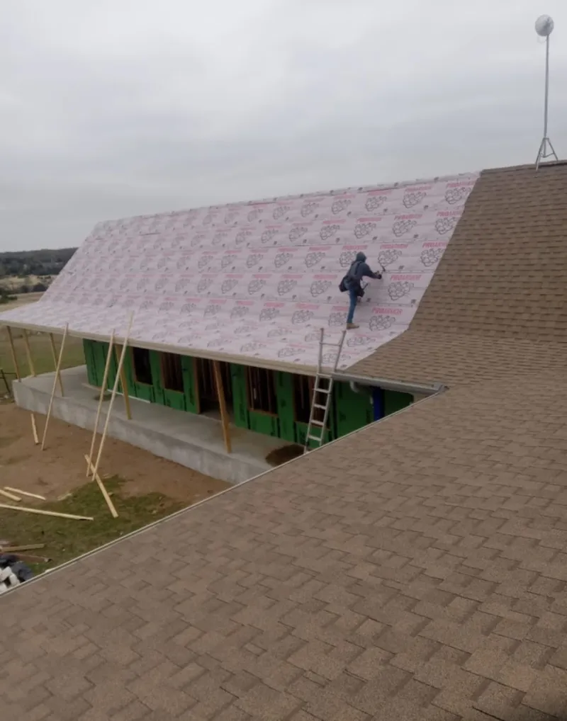 Worker preparing underlayment for a metal roof installation in Hollis